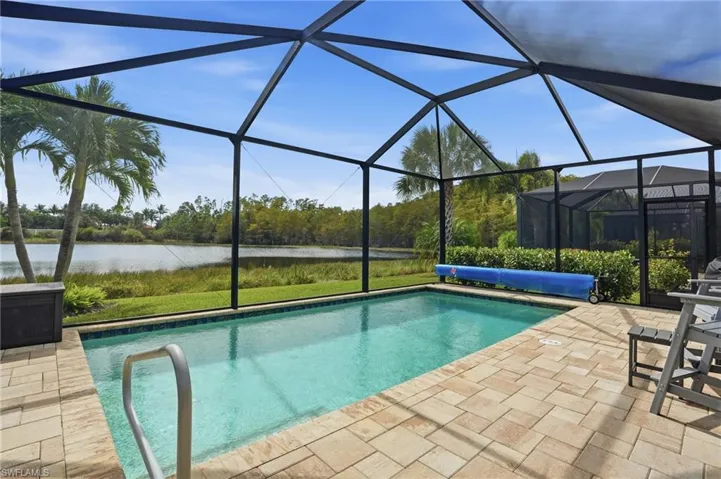 Outdoor pool with a lanai, a sunroom, a water view, and a patio area