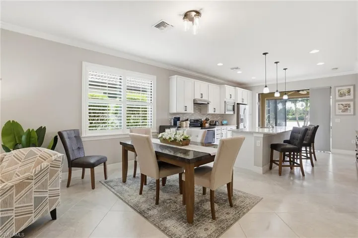 Dining space with ornamental molding, light tile patterned floors, and recessed lighting