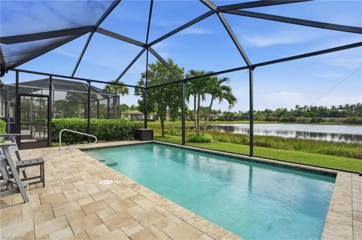 Outdoor pool with a water view, a sunroom, glass enclosure, and a patio