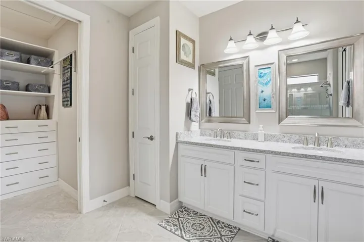 Bathroom featuring a closet, double vanity, and a shower with shower door