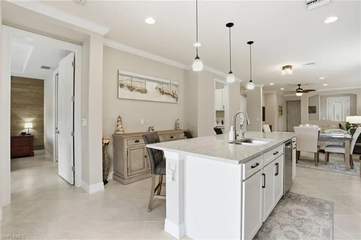 Kitchen featuring light stone counters, hanging light fixtures, crown molding, ceiling fan, and light tile patterned flooring
