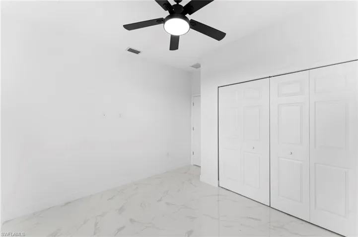 Unfurnished bedroom with ceiling fan, a closet, and light marble finish floors