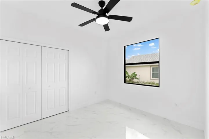 Unfurnished bedroom featuring light marble finish floors, a ceiling fan, and a closet