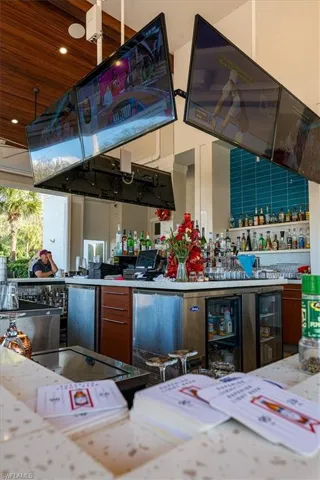 Kitchen featuring wood finish cabinets, light stone countertops, wooden ceiling, recessed lighting, and stainless steel fridge