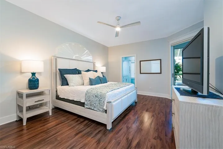 Bedroom featuring dark wood-style floors, ceiling fan, and ensuite bathroom