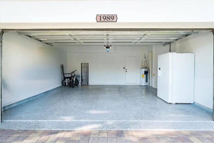 Garage with white refrigerator with ice dispenser and water heater