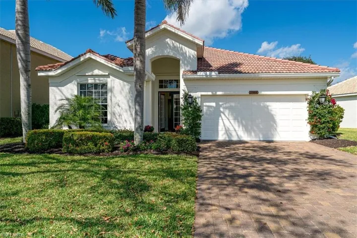 Mediterranean / spanish home with a tile roof, a garage, stucco siding, and driveway