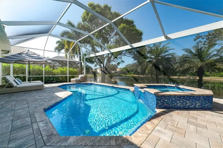 Relaxing pool / spa featuring a patio area, a water view, glass enclosure, and a sunroom