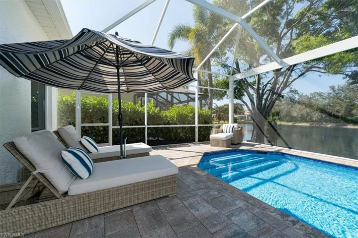 Swimming pool with a patio area, glass enclosure, a sunroom, and a water view