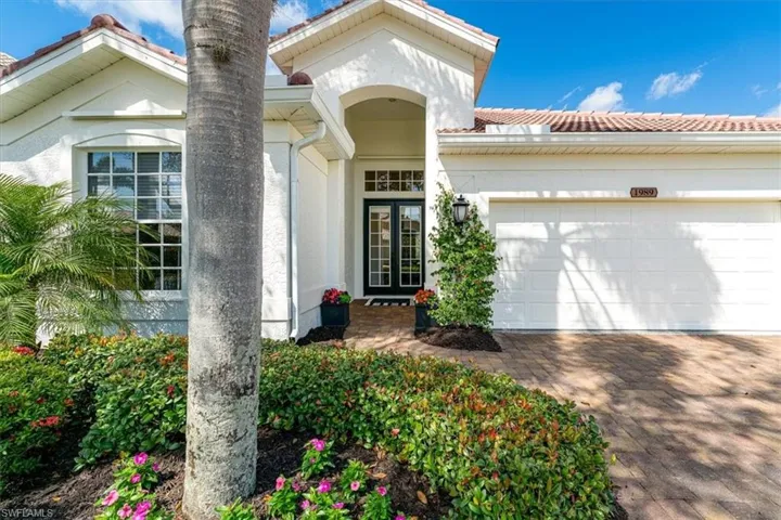 View of front of home featuring driveway, a garage, a tiled roof, stucco siding, and french doors