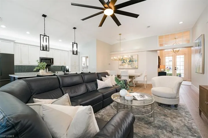 Living area featuring suspended lighting, wood finished floors, a ceiling fan, french doors, and vaulted ceiling