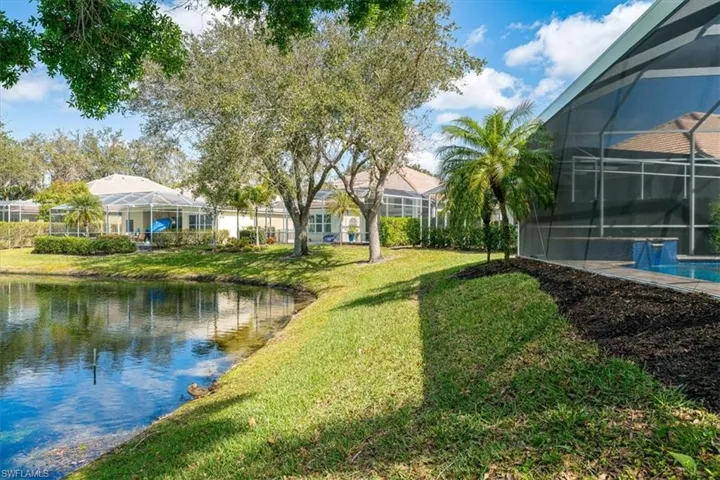 View of green lawn featuring a sunroom, glass enclosure, a water view, and an outdoor pool