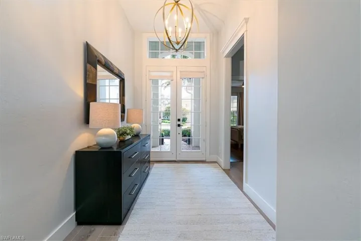 Entrance foyer featuring light wood-type flooring, suspended lighting, healthy amount of natural light, and french doors