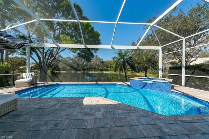 Integrated pool / spa featuring a sunroom, a water view, and glass enclosure