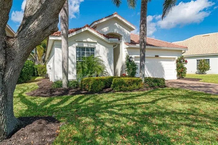 Mediterranean / spanish home with a garage, stucco siding, a front lawn, and a tile roof