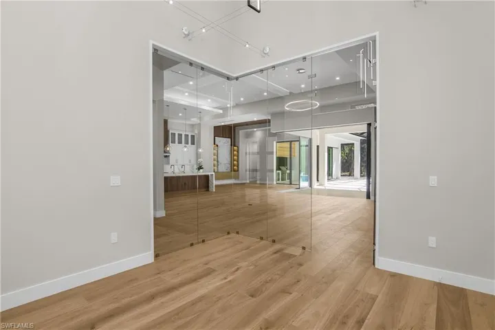 Unfurnished living room with light wood finished floors, recessed lighting, and a high ceiling