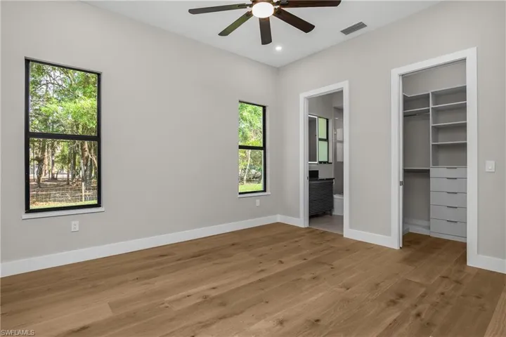 Unfurnished bedroom with a walk in closet, light wood-type flooring, recessed lighting, and a ceiling fan