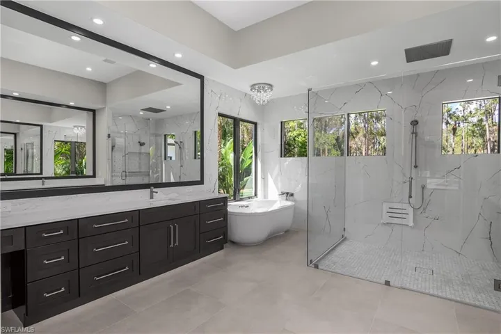 Full bathroom featuring a marble finish shower, healthy amount of natural light, a freestanding bath, and vanity