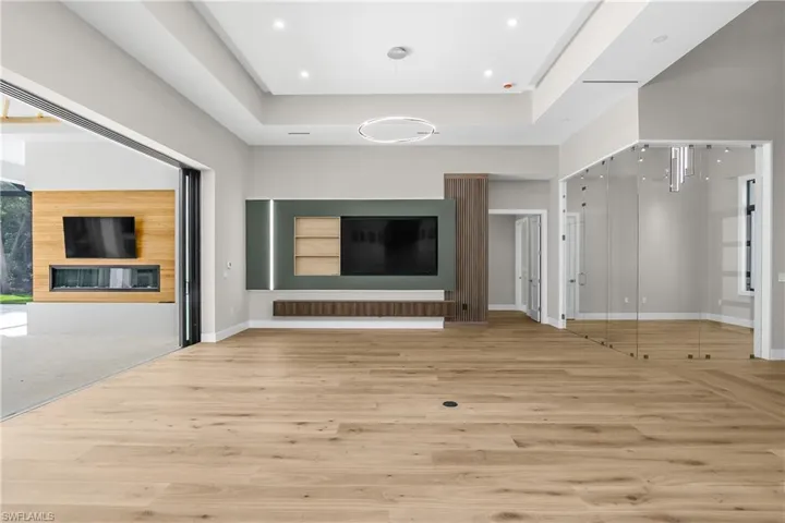 Unfurnished living room with light wood-style floors and a tray ceiling