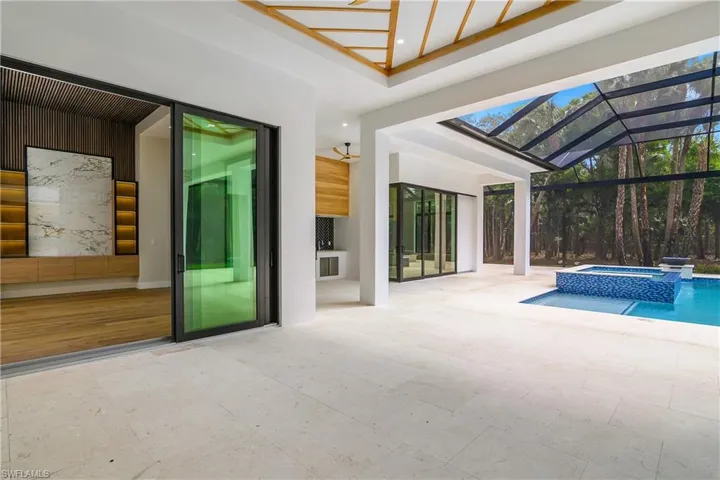 Combined pool / hot tub with glass enclosure, a patio, and a sunroom