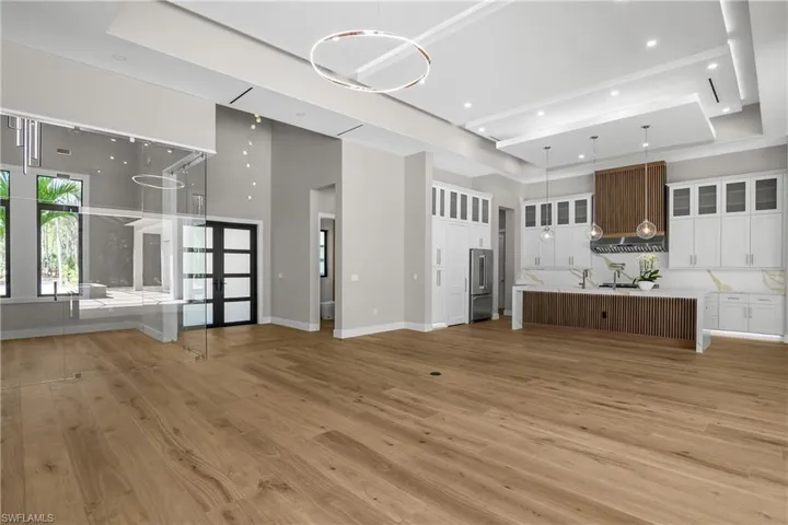 Unfurnished living room featuring light wood-style flooring and a tray ceiling