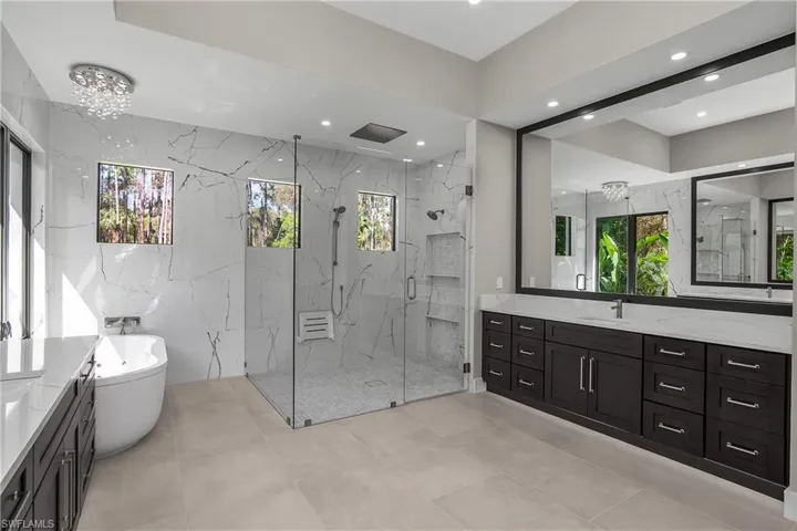 Bathroom with vanity, a freestanding tub, a marble finish shower, and recessed lighting