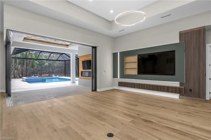 Unfurnished living room featuring a sunroom, a tray ceiling, and light wood-style flooring