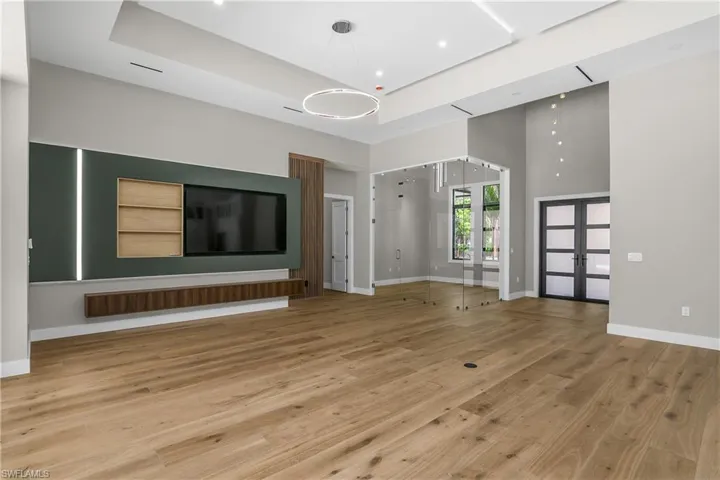 Unfurnished living room with french doors, a high ceiling, and light wood finished floors