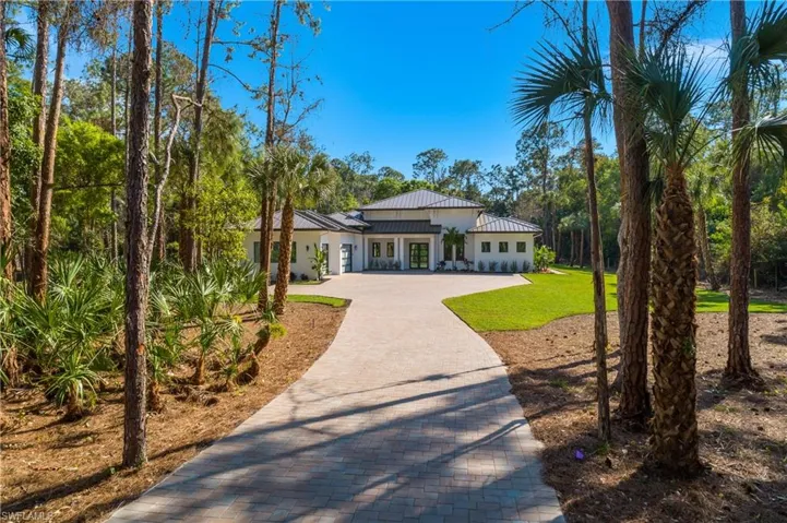 Front yard, decorative driveway, a metal roof, and a garage