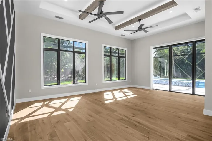 Empty room with a raised ceiling, light wood-style floors, ceiling fan, healthy amount of natural light, and recessed lighting