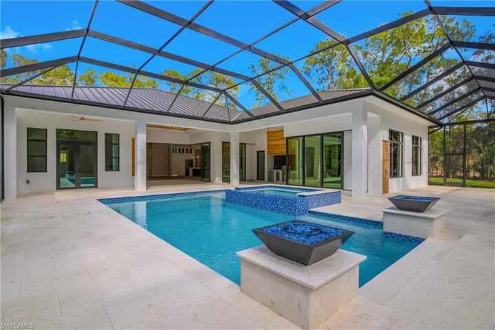 Relaxing pool / spa featuring glass enclosure, a sunroom, and a patio area