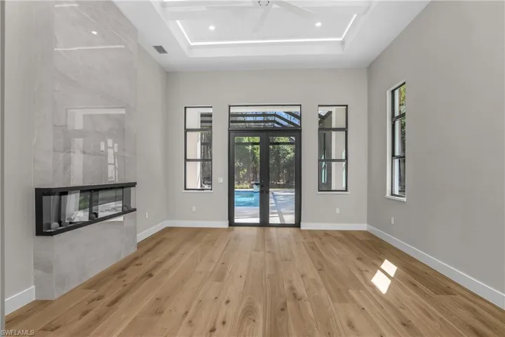 Unfurnished living room featuring french doors, light wood-style flooring, a ceiling fan, a fireplace, and a sunroom