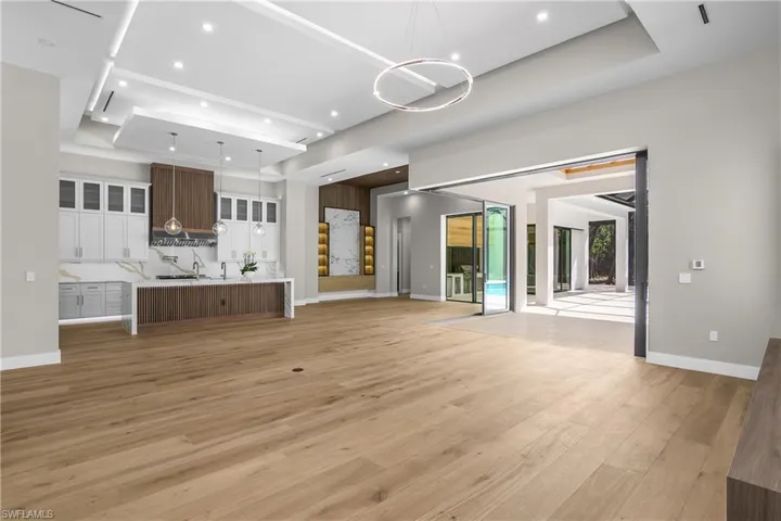 Unfurnished living room with a raised ceiling, light wood-type flooring, and recessed lighting