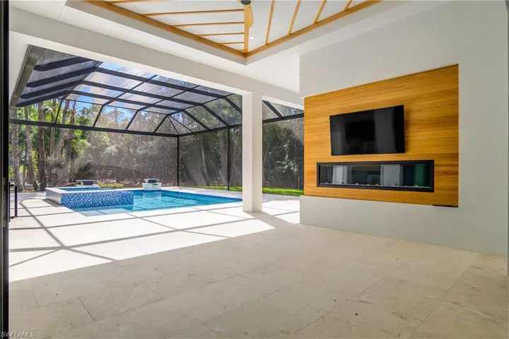 Combined pool / hot tub featuring glass enclosure, a patio, and a sunroom