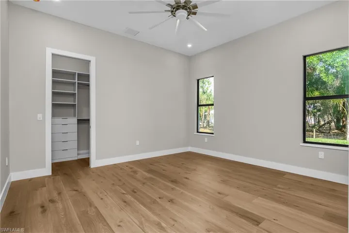 Unfurnished bedroom with a walk in closet, light wood-type flooring, recessed lighting, and a ceiling fan