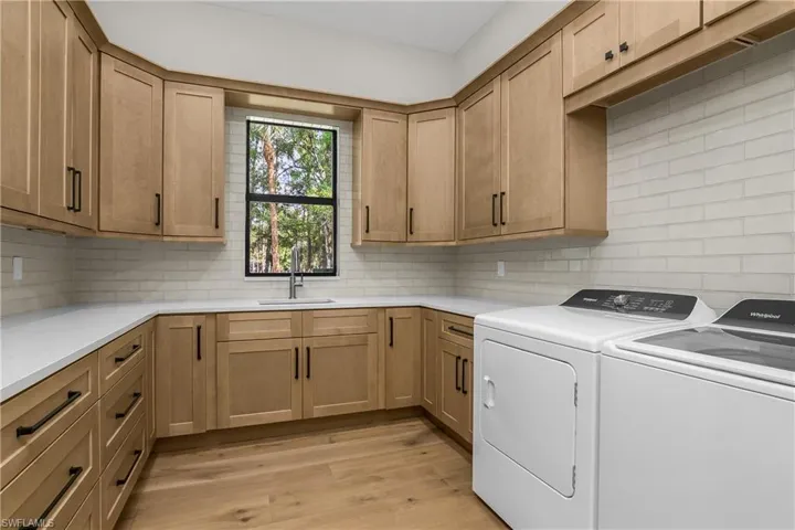 Laundry area with light wood-type flooring, independent washer and dryer, and cabinet space
