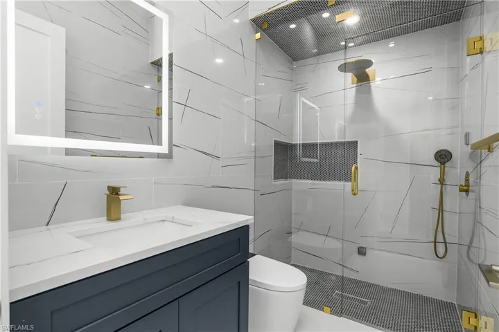 Full bath with a marble finish shower, vanity, and tile walls