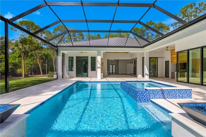 Integrated pool / hot tub with a sunroom, a lanai, and a patio