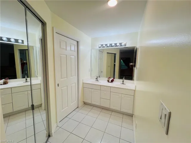 Ensuite bathroom featuring light tile patterned floors and double vanity