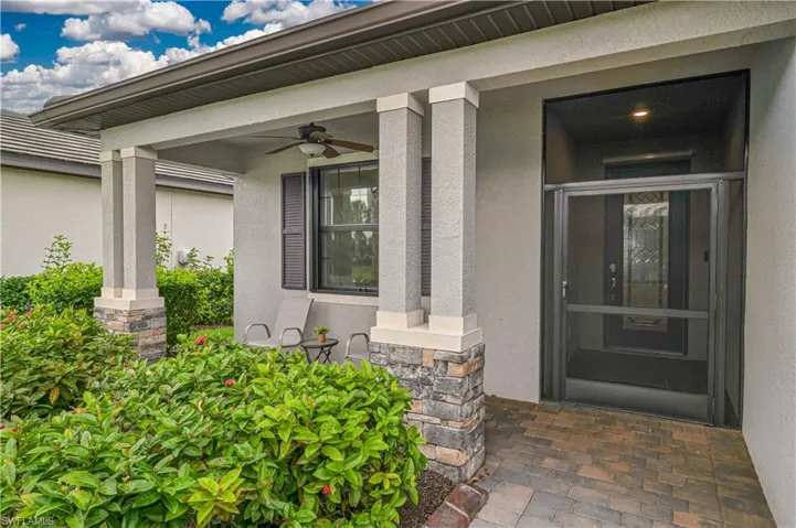 Property entrance featuring stone siding, stucco siding, covered porch, and a ceiling fan