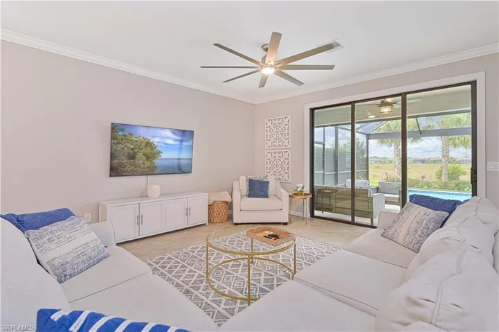Living area with light tile patterned floors, a ceiling fan, and ornamental molding
