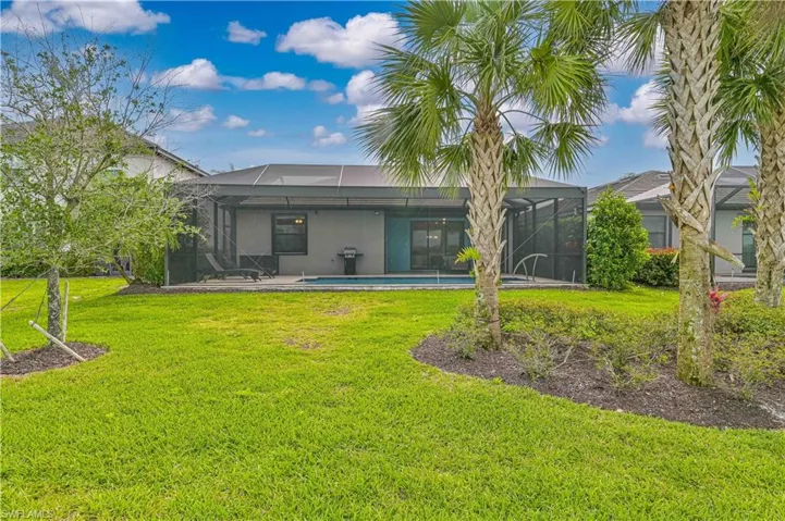 Rear view of house featuring an outdoor pool, glass enclosure, a lawn, and stucco siding
