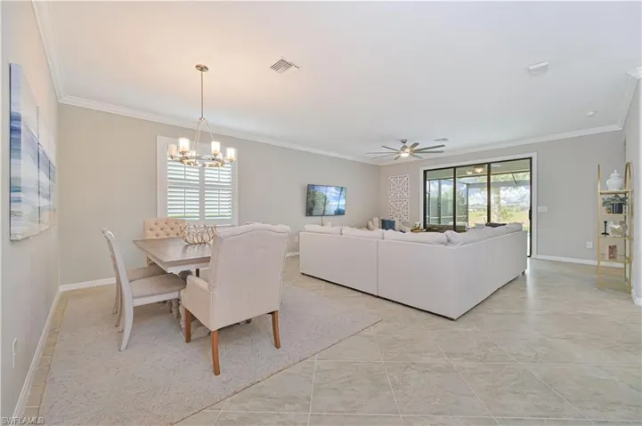 Dining area featuring plenty of natural light, ceiling fan with notable chandelier, crown molding, and baseboards