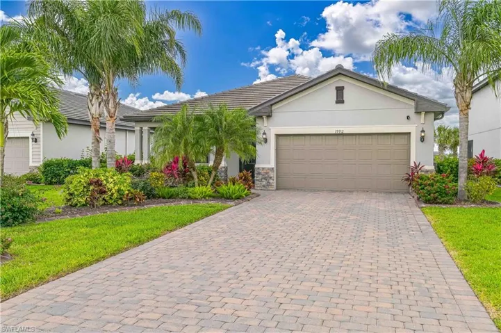 Ranch-style house with stone siding, stucco siding, decorative driveway, and an attached garage