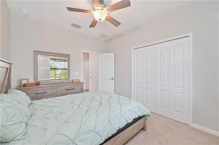 Bedroom featuring a ceiling fan, visible vents, baseboards, a closet, and light colored carpet