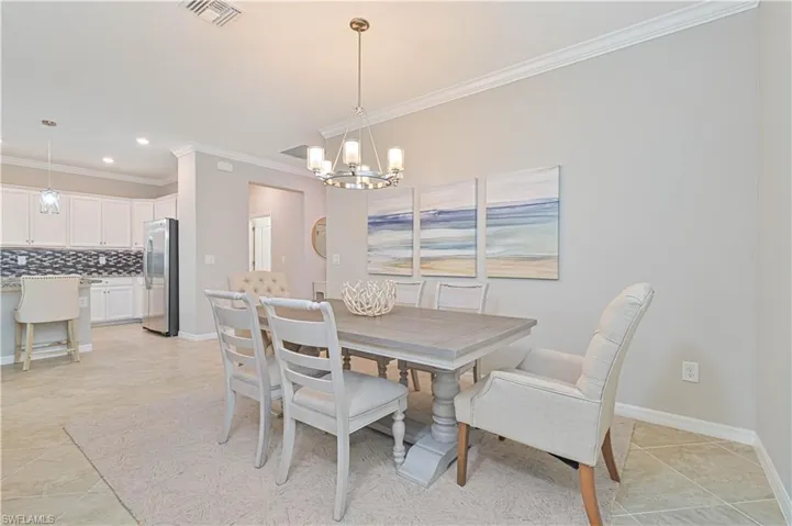 Dining space with visible vents, baseboards, an inviting chandelier, and ornamental molding