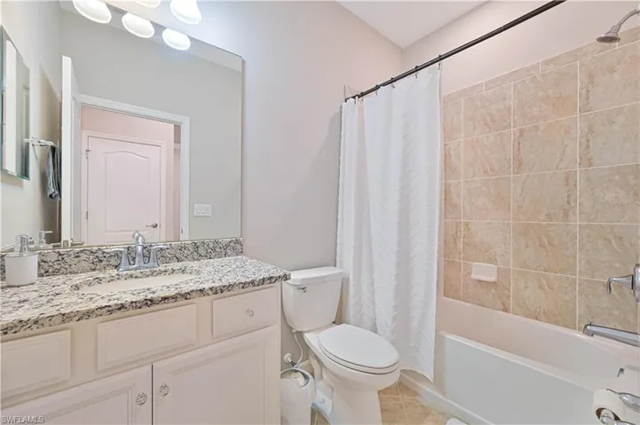 Bathroom featuring tile patterned floors, shower / bath combination with curtain, toilet, and vanity