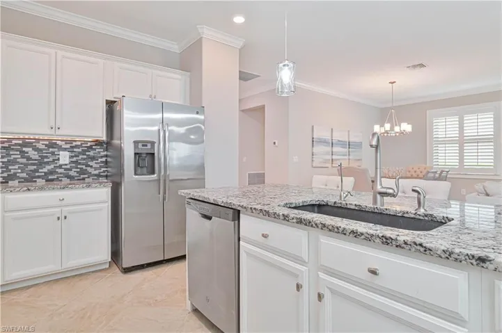 Kitchen featuring visible vents, ornamental molding, white cabinets, stainless steel appliances, and a sink
