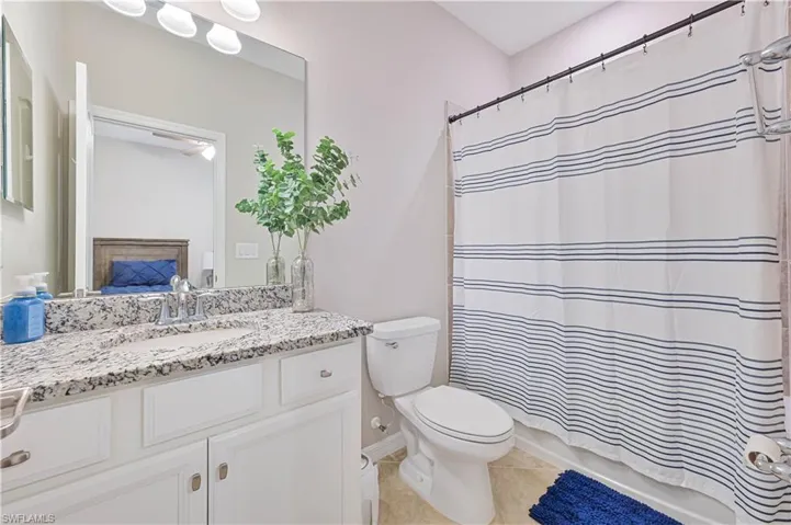 Bathroom featuring toilet, ensuite bathroom, a fireplace, tile patterned flooring, and vanity