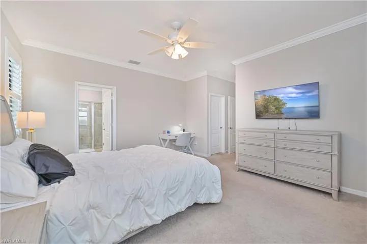 Bedroom with visible vents, baseboards, light colored carpet, and ornamental molding